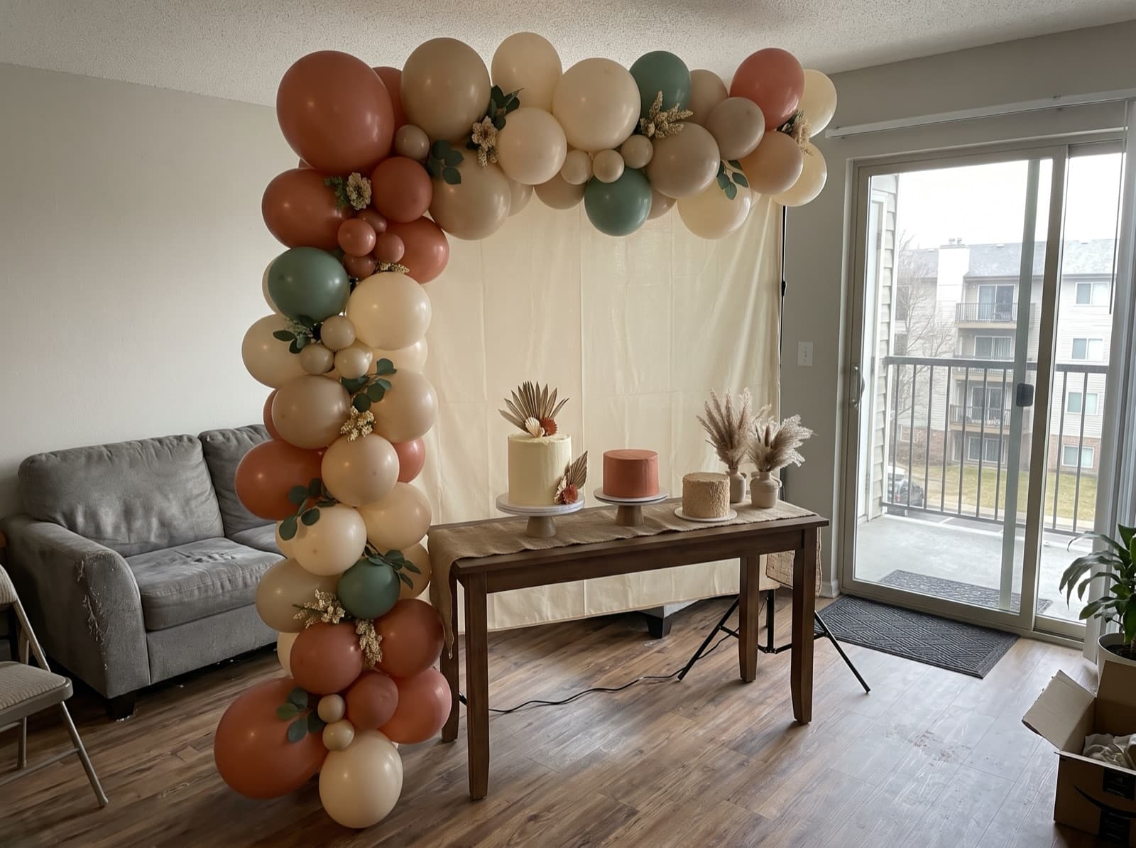 Half balloon arch swooping over a cake table in a condo